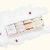 Gift set with four skincare jars in a white box on a fluffy white surface