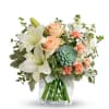 Bouquet of white lilies, peach roses, and blue-green blooms in a clear vase