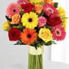 Colorful bouquet of gerbera daisies and roses in a glass vase