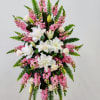 A tall, graceful spray of white lilies and pale cream roses framed