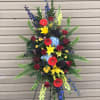 Tall standing floral spray with red, yellow, blue, and purple blooms