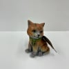 Small painted cat figurine with a green collar and feather wing