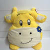 Yellow plush cow pillow with a smiling face and blue flower detail