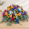 Large colorful floral arrangement with a blue ribbon on a table
