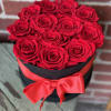 Red roses arranged in a black round box with a red ribbon