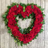 Heart-shaped wreath of red roses and greenery on a wood background