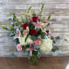 Bouquet of red roses, pink lilies, and white hydrangeas in a glass vase