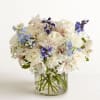 White and blue mixed bouquet in a clear glass vase