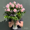 Pink roses in a clear glass vase with purple filler flowers