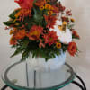Orange chrysanthemum arrangement in a white pumpkin vase