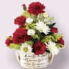 Red and white flowers arranged in a handled mug