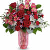 Bouquet of red and pink flowers in a pink glass vase