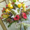 Bouquet of yellow roses, white calla lilies, and pink gerbera daisies in a glass vase