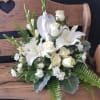 White floral arrangement with lilies and roses on a wooden bench