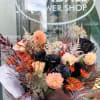 Bouquet of peach, orange, and black flowers wrapped in dark paper