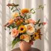 Mixed bouquet in a peach vase with pink, yellow, and cream flowers