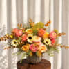 Colorful floral arrangement in a round vase with pink, peach, yellow, and orange blooms