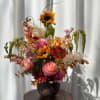 Mixed bouquet in a dark vase with sunflowers, pink blooms, and orange flowers