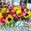 Bright bouquet with sunflowers, pink roses, and magenta flowers in a white container