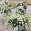 Large white floral funeral sprays with roses and lilies on stands
