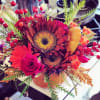 Bright mixed bouquet with sunflowers, roses, and orange blooms in a vase
