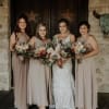 Bride and three bridesmaids holding mixed bouquets in front of a rustic doorway