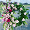Pink and white floral wreath on a stand with roses and lilies