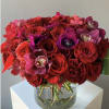 Red and pink bouquet of roses and orchids in a clear glass vase