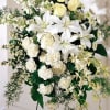 White lilies and pale yellow roses in a standing floral spray
