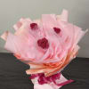 Bouquet of three pink roses wrapped in pale pink paper
