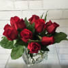 Red roses arranged in a clear square glass vase