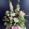 This charming baby arrangement features soft, cheerful blooms nestled inside a classic