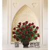 Red roses arranged in a dark vase on a table with framed photos