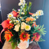 Mixed bouquet in a white mug with orange and white flowers and red ribbon