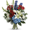 Bouquet of red roses, white lilies, and blue flowers in a glass vase