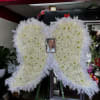 White floral heart-shaped funeral spray with a framed photo in the center
