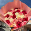 Bouquet of pink, red, and white roses wrapped in pink paper