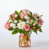 Pink roses and white daisies arranged in a pink glass vase