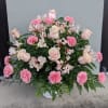 Pink roses and carnations arranged in a white basket.