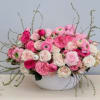 Low centerpiece of pink and white blooms in a white ceramic bowl