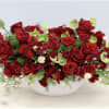 Red roses and pale green flowers in a white bowl vase