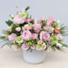 Low white vase filled with pink roses, peonies, tulips and green hydrangea blooms
