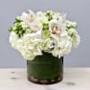 White hydrangeas and orchids arranged in a glass vase