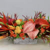 Tropical floral arrangement with orange and red blooms in a rectangular container