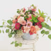Mixed bouquet of pink, peach, and white flowers in a metal bucket