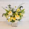 Yellow and white floral arrangement in a square silver vase
