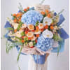 Bouquet of blue hydrangeas, orange roses, and white orchids with a birthday card