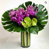 Purple orchids and green anthuriums in a tall glass vase