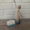 Decorative figurine of a woman in a long dress with one arm raised