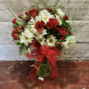Bouquet of red and white flowers in a glass vase with a red ribbon